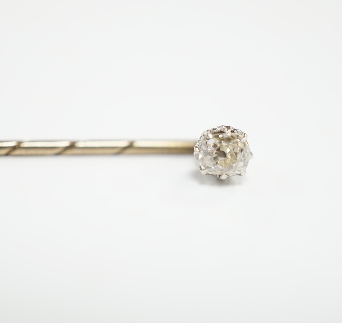 An early 20th century cased yellow metal and cushion cut solitaire diamond set stick pin, 57mm, gross weight 1.3 grams.